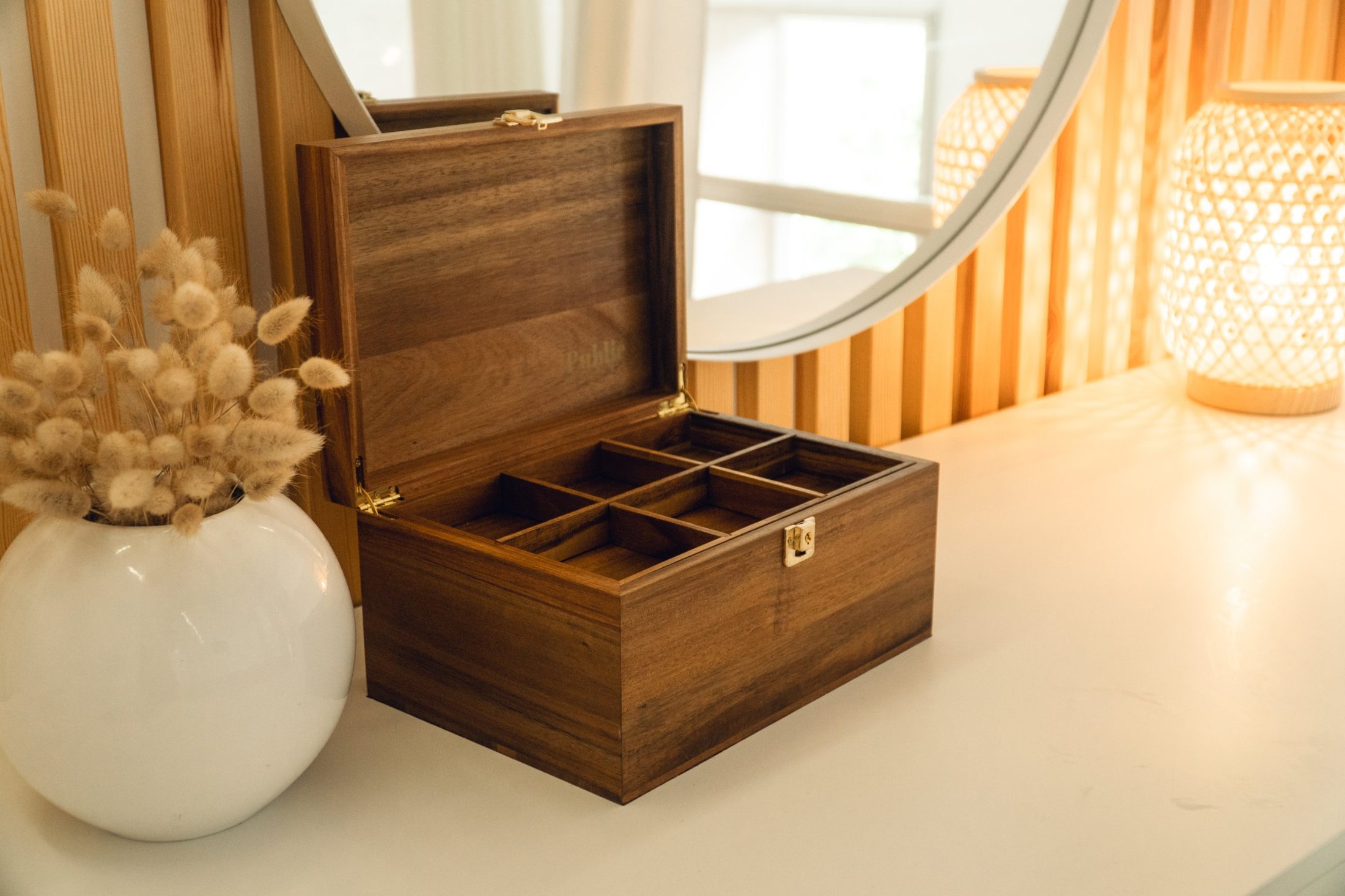 A Public House timber keepsake box open on a sideboard beside a vase of dried grasses