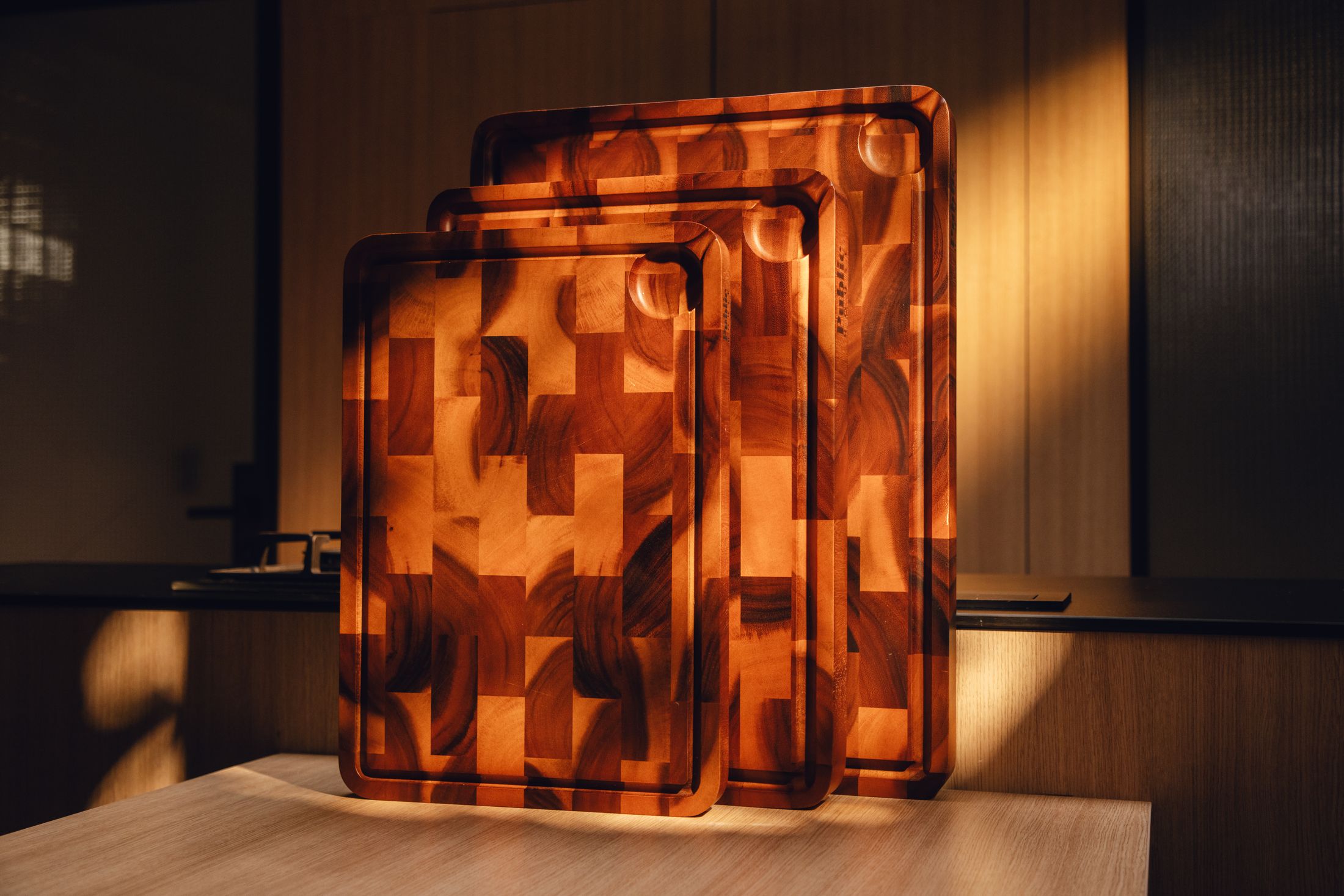 Three Public House end-grain acacia boards standing in warm evening light